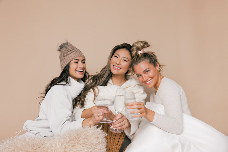 Three happy women laughing while they cheers their glasses. How to make a healthy habit for hair growth going into the new year