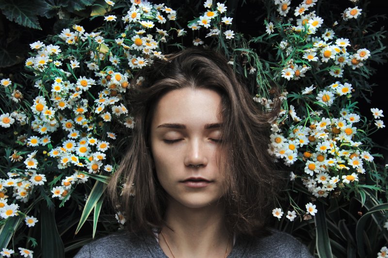 woman-eyes-closed-chamomile-flower-background