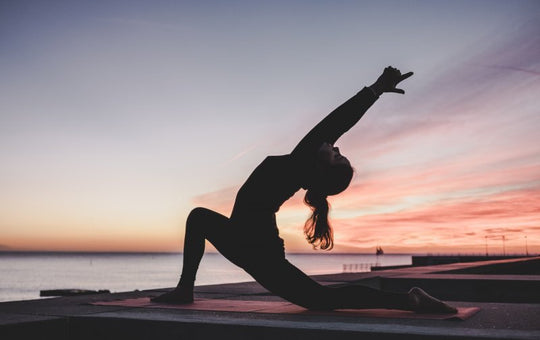 woman-doing-crescent-moon-yoga-pose-at-sunset